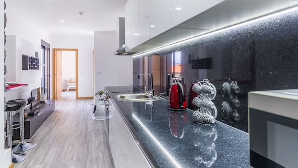 A modern kitchen with a long countertop, stainless steel appliances, and a backsplash.