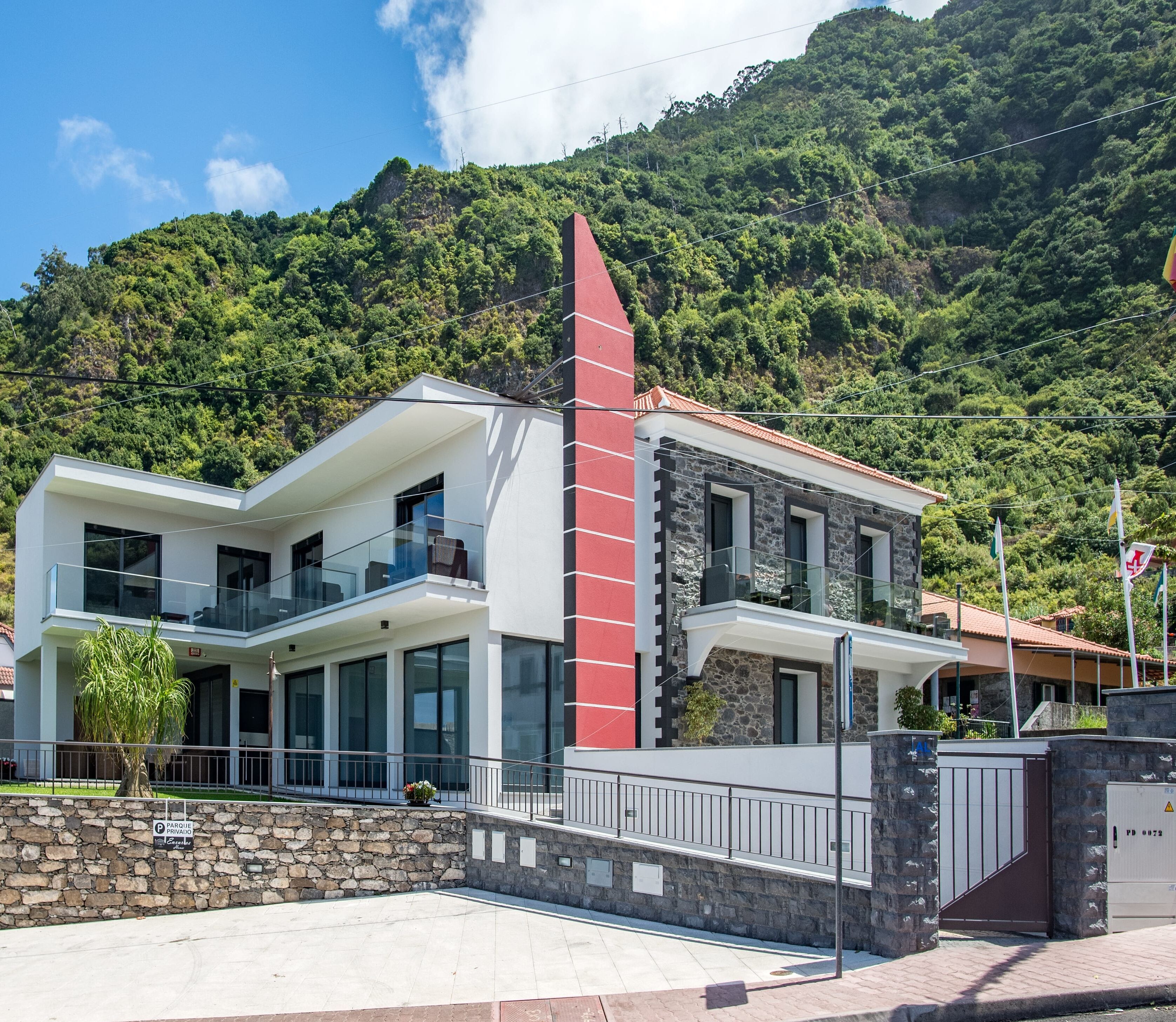 A modern two-story house with a stone facade, large windows, and a balcony.