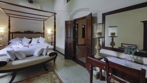 A four-poster bed with white linens, a wooden nightstand with a vase of flowers, and a large mirror above a wooden dresser. - Satiana Villa Tangalle (Tangalle)