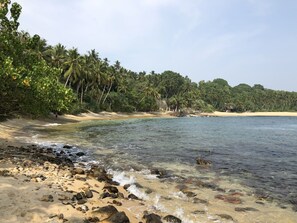 A beach with clear water, sandy shore, and dense palm trees. - Satiana Villa Tangalle (Tangalle)
