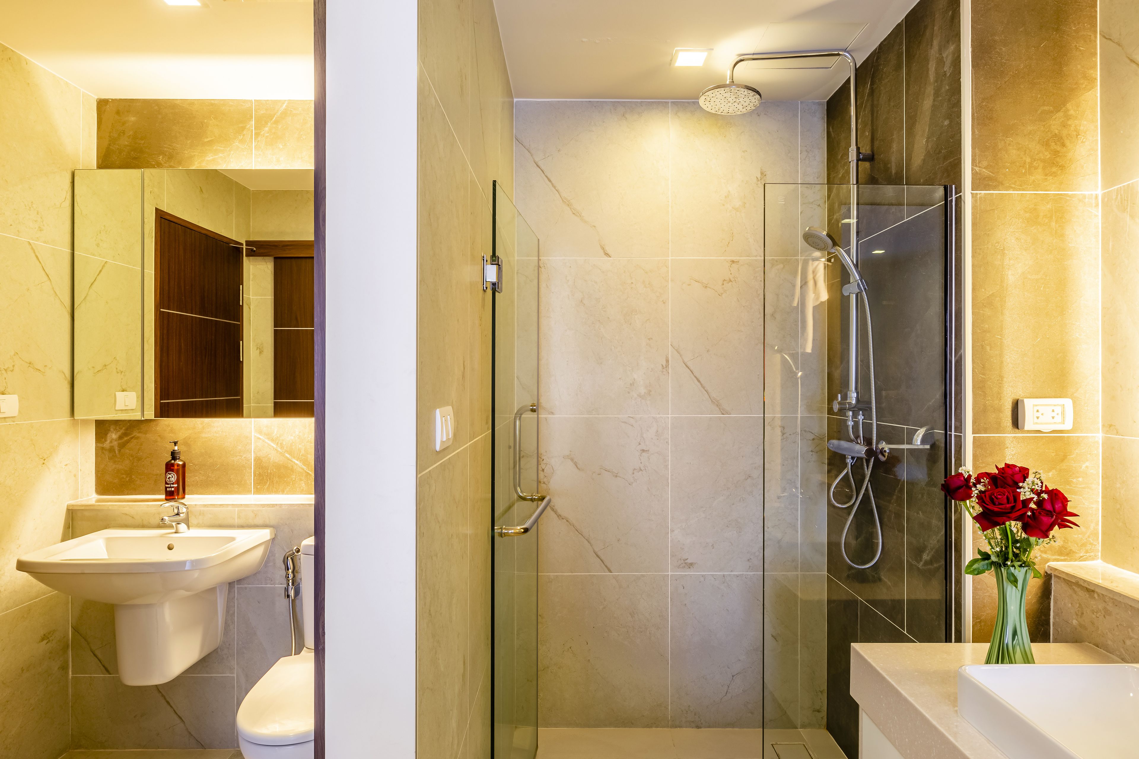 A modern bathroom with a glass-enclosed shower, a sink, and a toilet.
