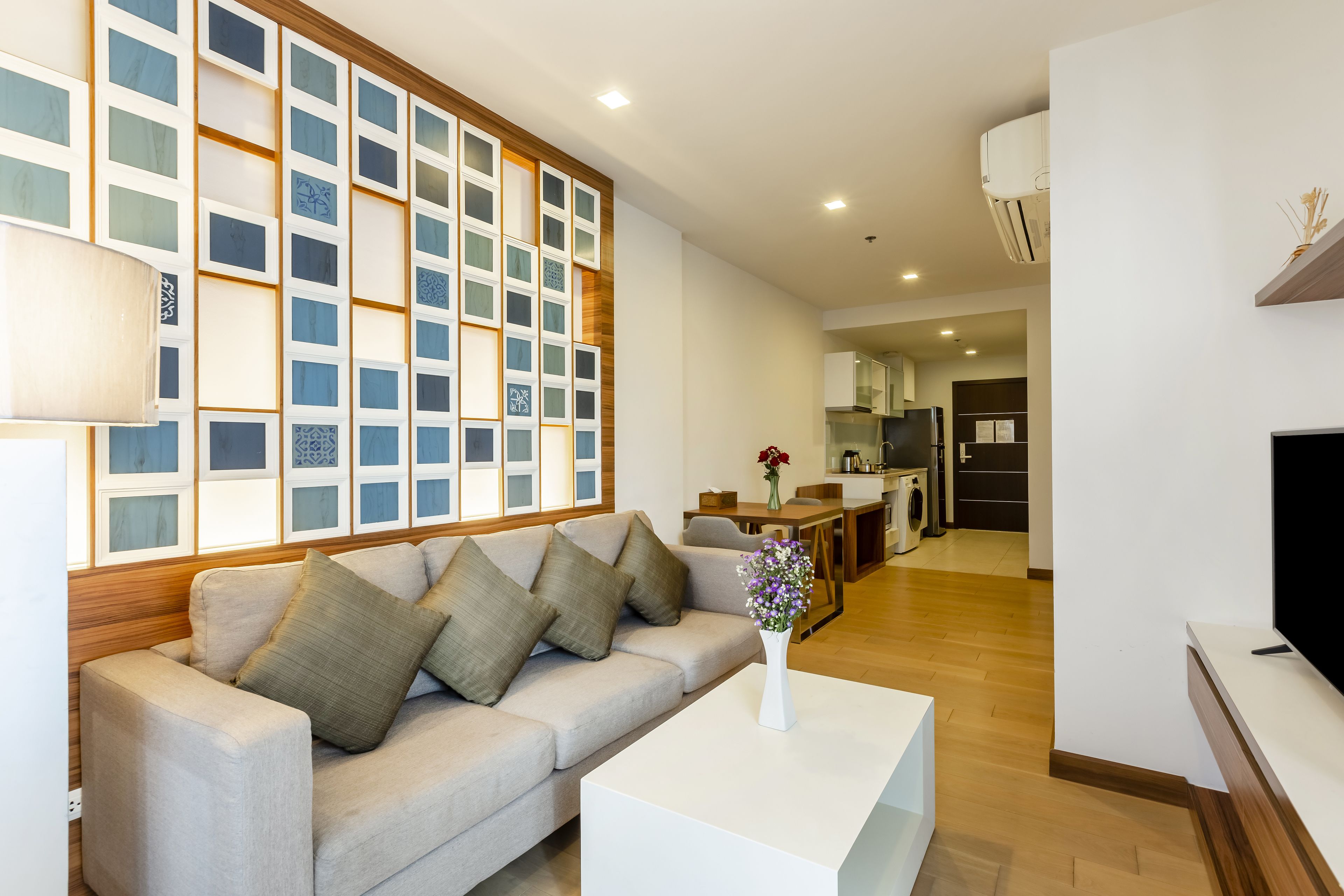 A modern living room with a sofa, a coffee table, and a wall-mounted TV.