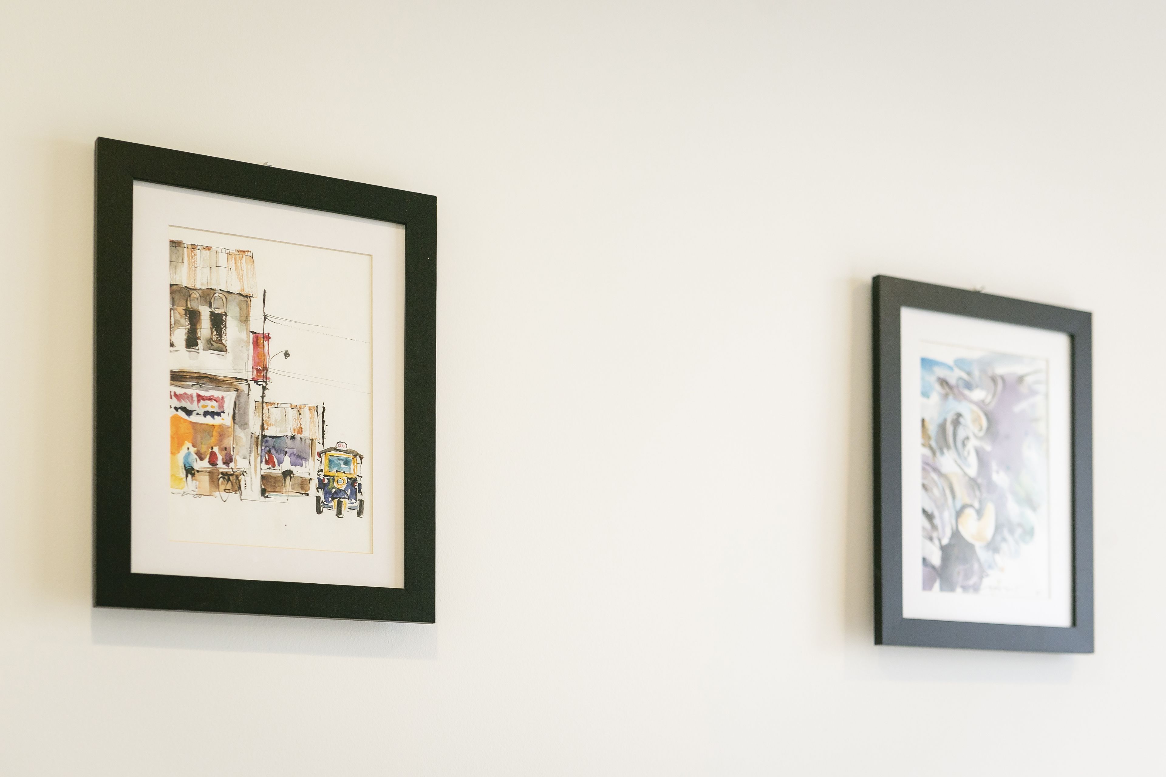 Two framed artworks on a plain wall.