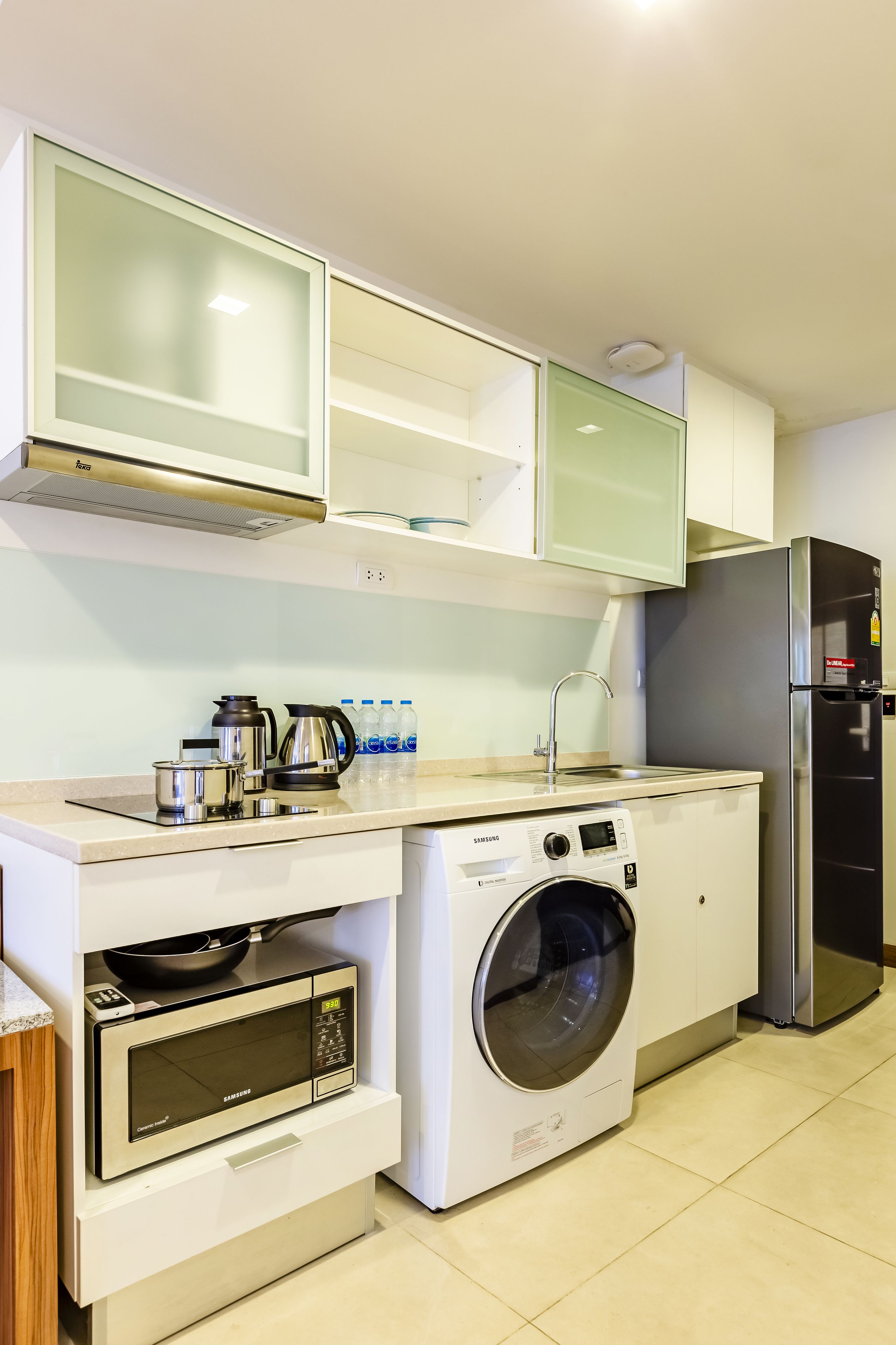 Une cuisine compacte équipée d’un four à micro-ondes, d’un four et d’un lave-linge.