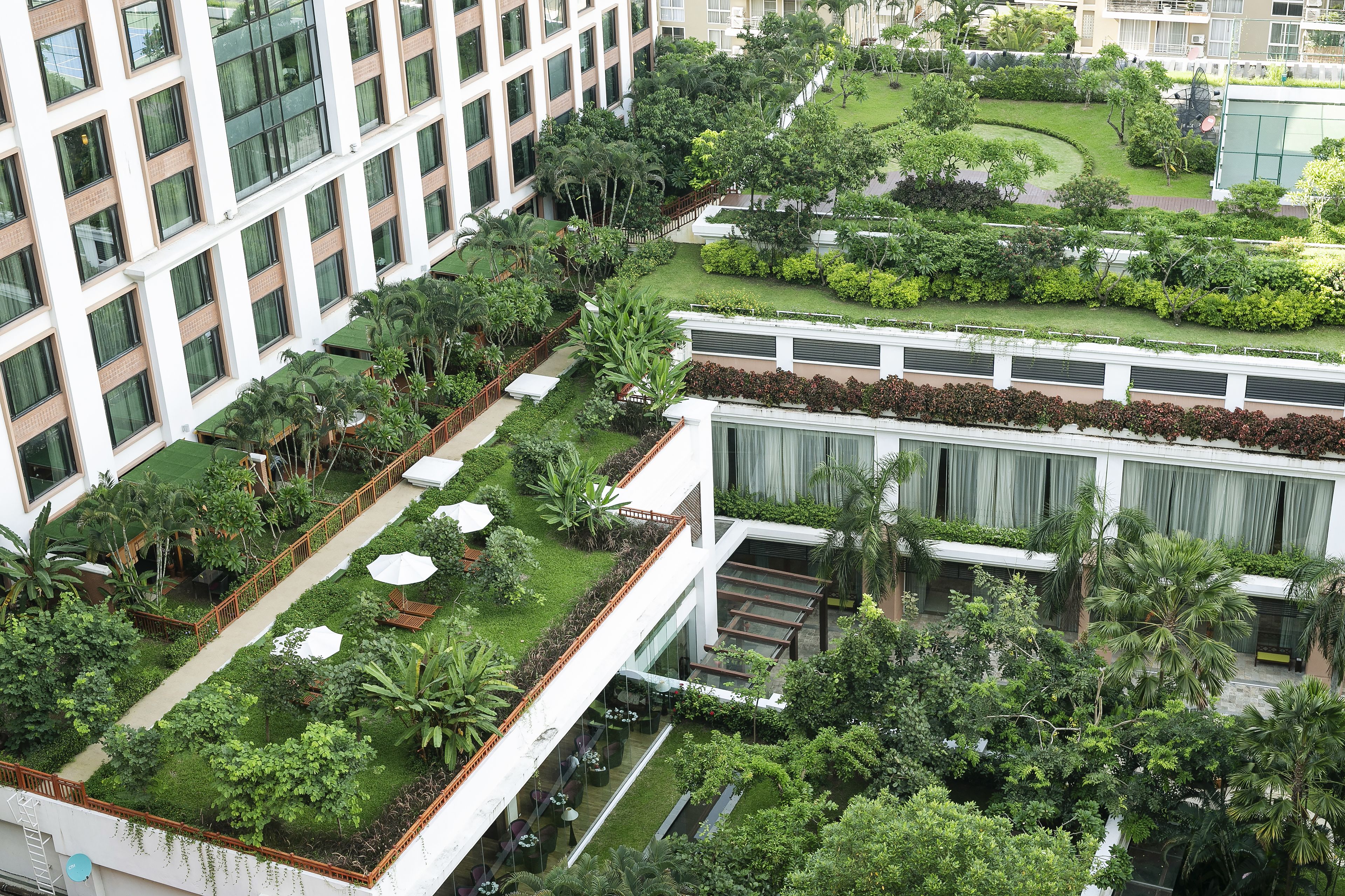 A multi-story hotel with a rooftop garden, outdoor seating areas, and a well-maintained courtyard.