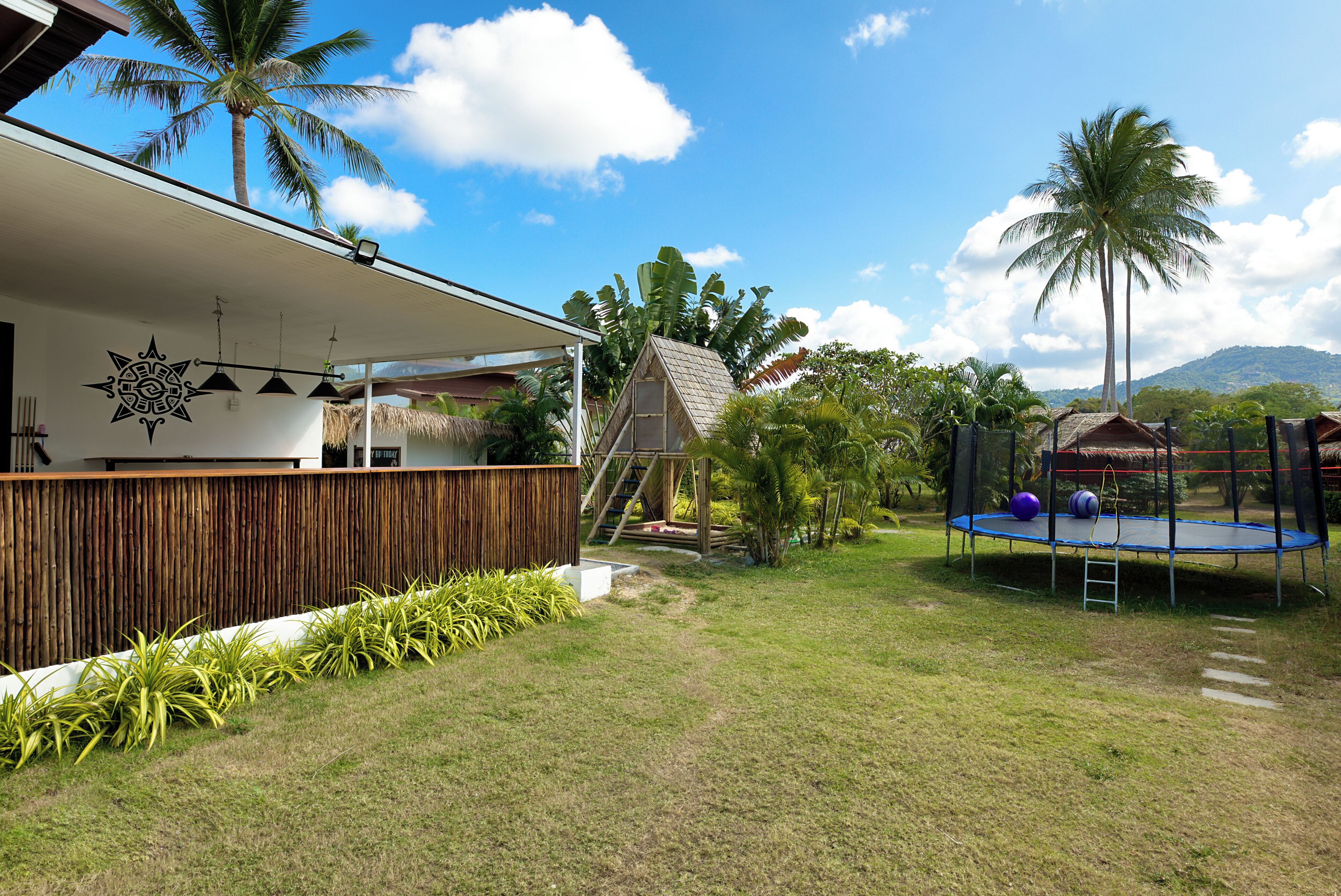 A modern house with a covered patio, a wooden deck, and a trampoline.