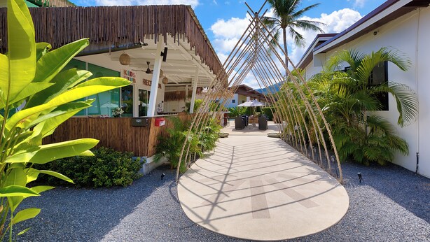 A pathway leading to a building with a thatched roof and a wooden fence. - Maya Resort (Koh Samui)