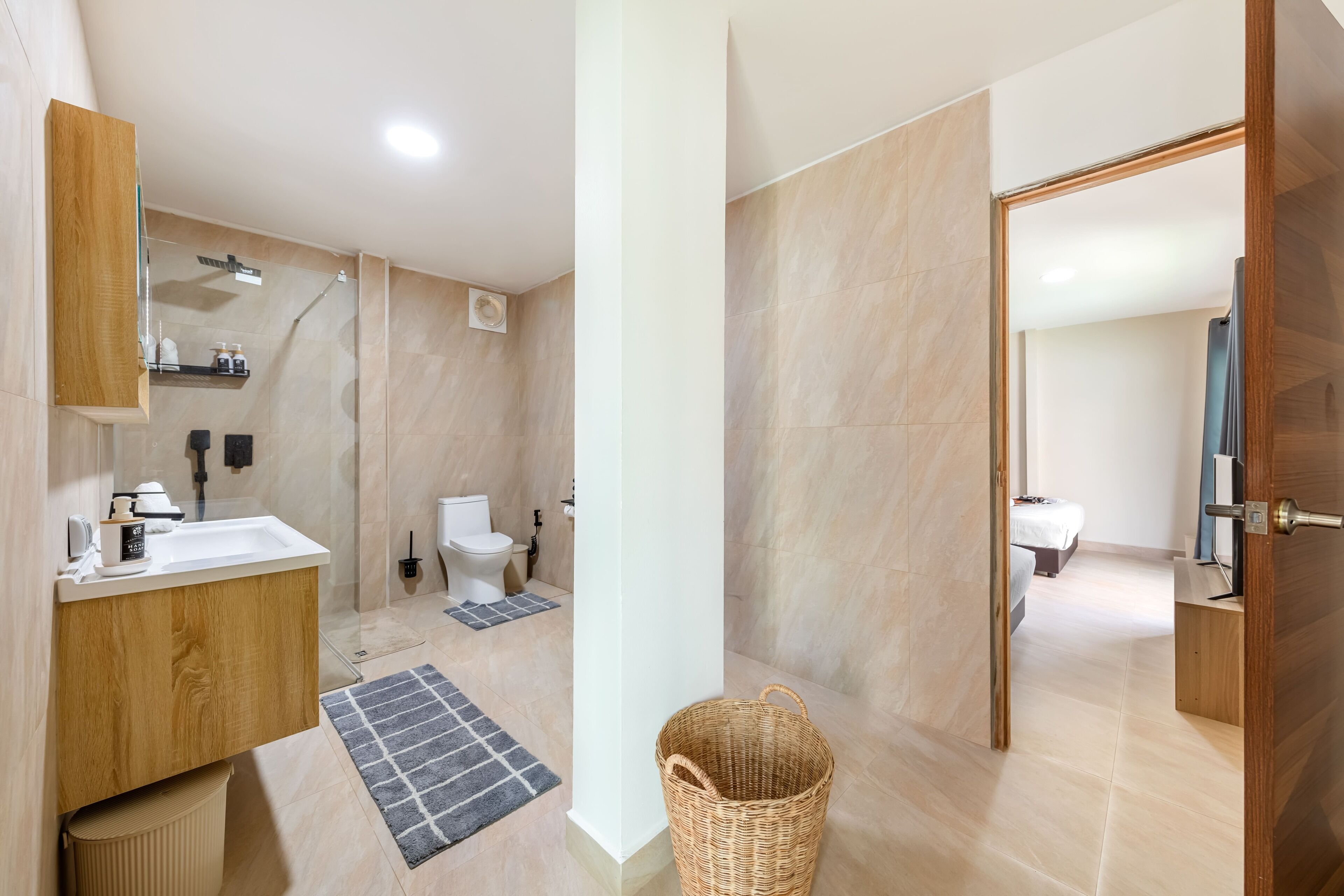 Ein modernes Badezimmer mit Dusche, Toilette und Waschbecken, Holzschränken und einem Korbwäschesammler.