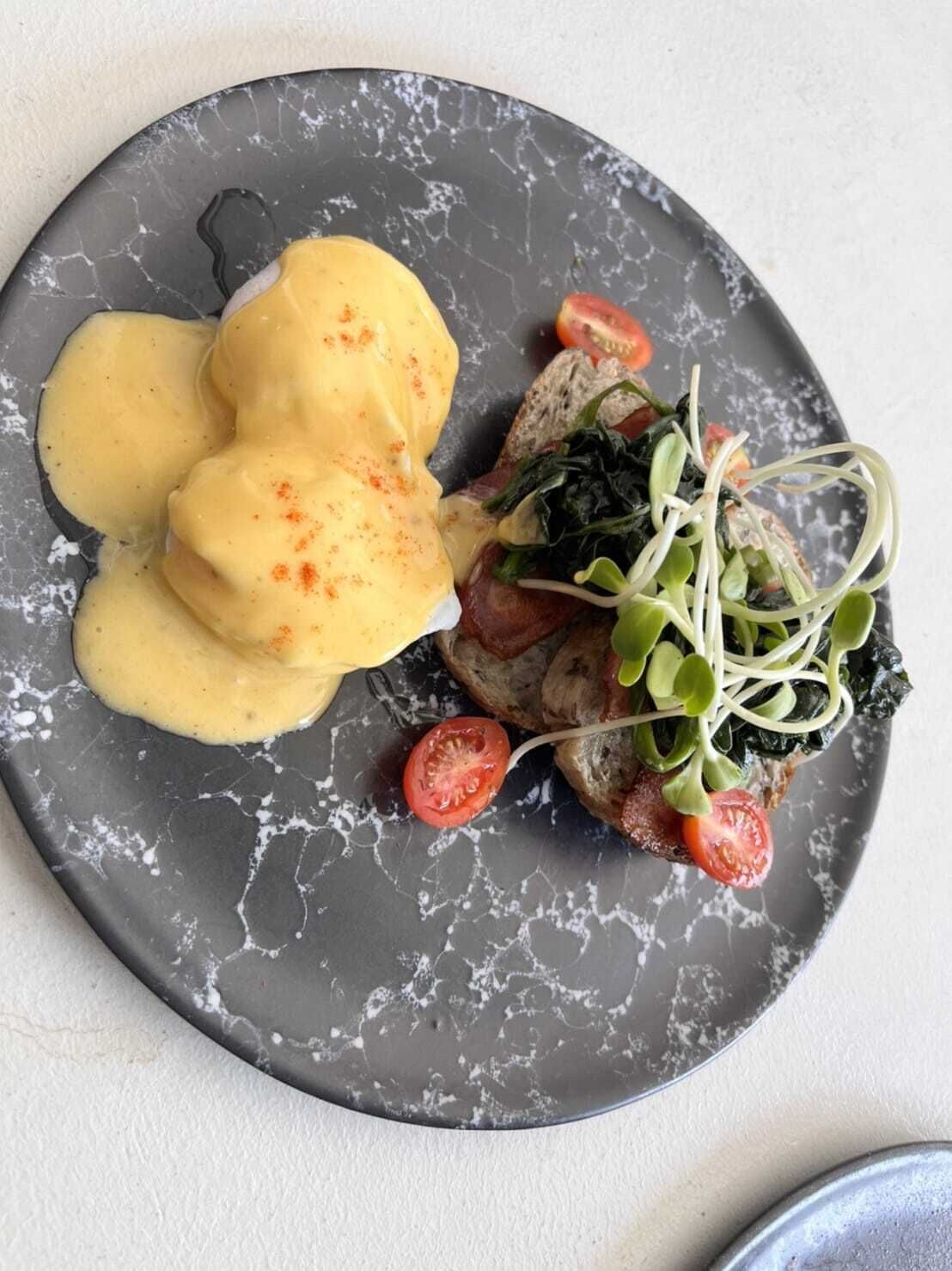 A plate with food consisting of poached eggs, greens, and tomatoes.