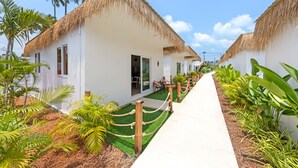 A row of white buildings with thatched roofs, surrounded by lush greenery and a clear sky. - Maya Resort (Koh Samui)