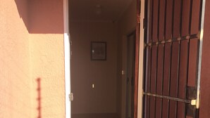 An open door leading into a hallway with a tiled floor and a metal gate on the right. - Essence of Africa Guesthouse (Windhoek)