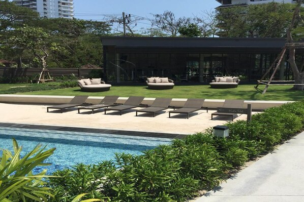 A modern outdoor pool area with lounge chairs and a building in the background.