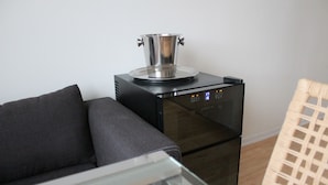 A modern kitchen with a stainless steel pot on a black induction cooktop, a dark sofa, and a wicker chair. - Apartmán Relax so saunou a jakuzzi (Namestovo)