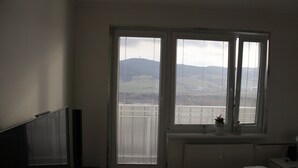 A bedroom with a bed, a TV, and a window with blinds. - Apartmán Relax so saunou a jakuzzi (Namestovo)