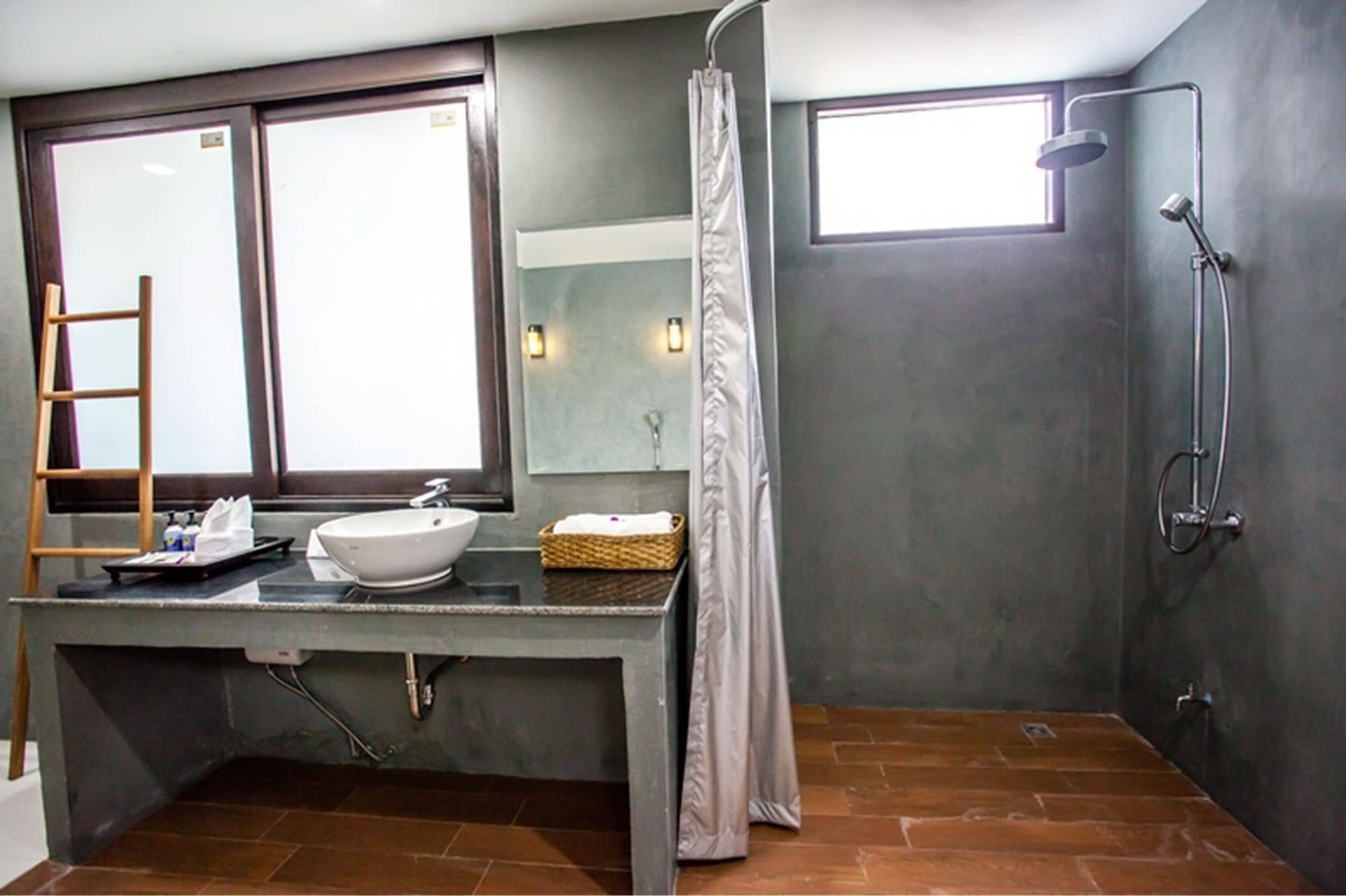 A bathroom with a large mirror, a sink, a shower, and a window.