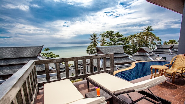 Un balcon avec vue sur la mer, une piscine et des chaises longues.