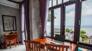 Une pièce avec un bureau en bois, un ordinateur portable et une vue sur la mer.