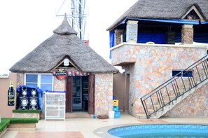 A building with a stone facade and a thatched roof, a pool, and a sign reading "GOLDBERG". - Groovy Hotel (Akure)