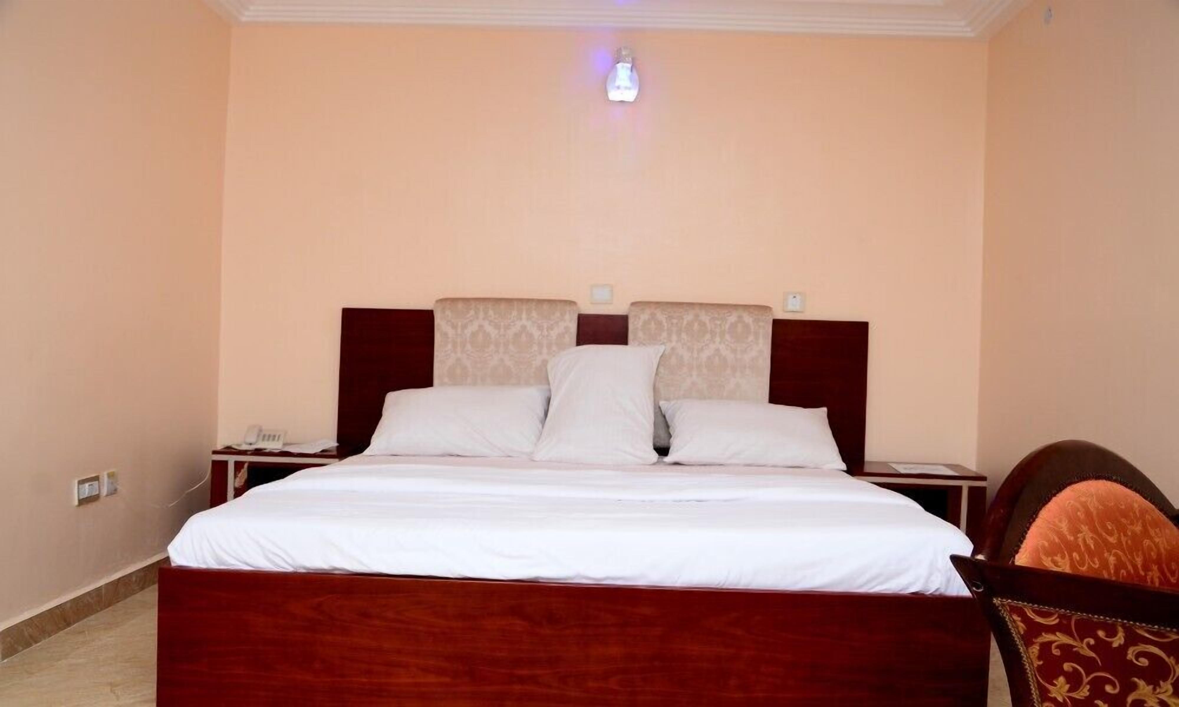 Een hotelkamer met een groot bed, twee nachtkastjes en een bijzettafeltje met een telefoon.