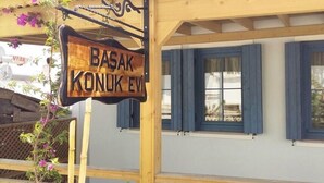 A wooden sign with the text "BASAK KONUK EVI" hanging from a structure. - Bozcaada Basak Konukevi (Bozcaada)