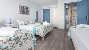 A hotel room with two beds, a ceiling fan, a shower area, and a door leading to another room. - Bozcaada Basak Konukevi (Bozcaada)