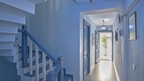 A hallway with a wooden floor, a staircase with blue railings, and a ceiling light fixture. - Bozcaada Basak Konukevi (Bozcaada)