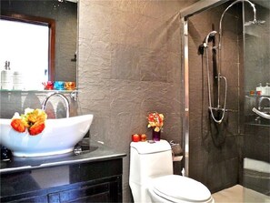 Un baño moderno con un lavamanos grande de color blanco, un inodoro y una zona de ducha.