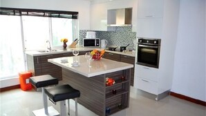 A modern kitchen with a central island, a microwave, an oven, and a sink.