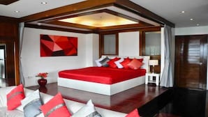 A modern hotel room with a large bed, a red accent wall, and a geometric art piece.