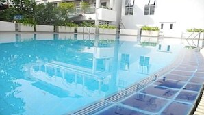 A swimming pool with a tiled edge, surrounded by a white building with balconies.