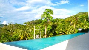 Une piscine à l’eau d’un bleu cristallin, entourée d’une végétation luxuriante et de palmiers.