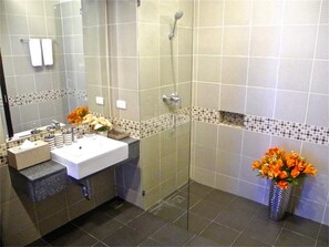 Un baño moderno con ducha de vidrio, un lavabo blanco y un florero con flores.