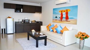Un salon moderne avec un canapé blanc, une table basse et un tableau représentant deux personnages sur une plage.