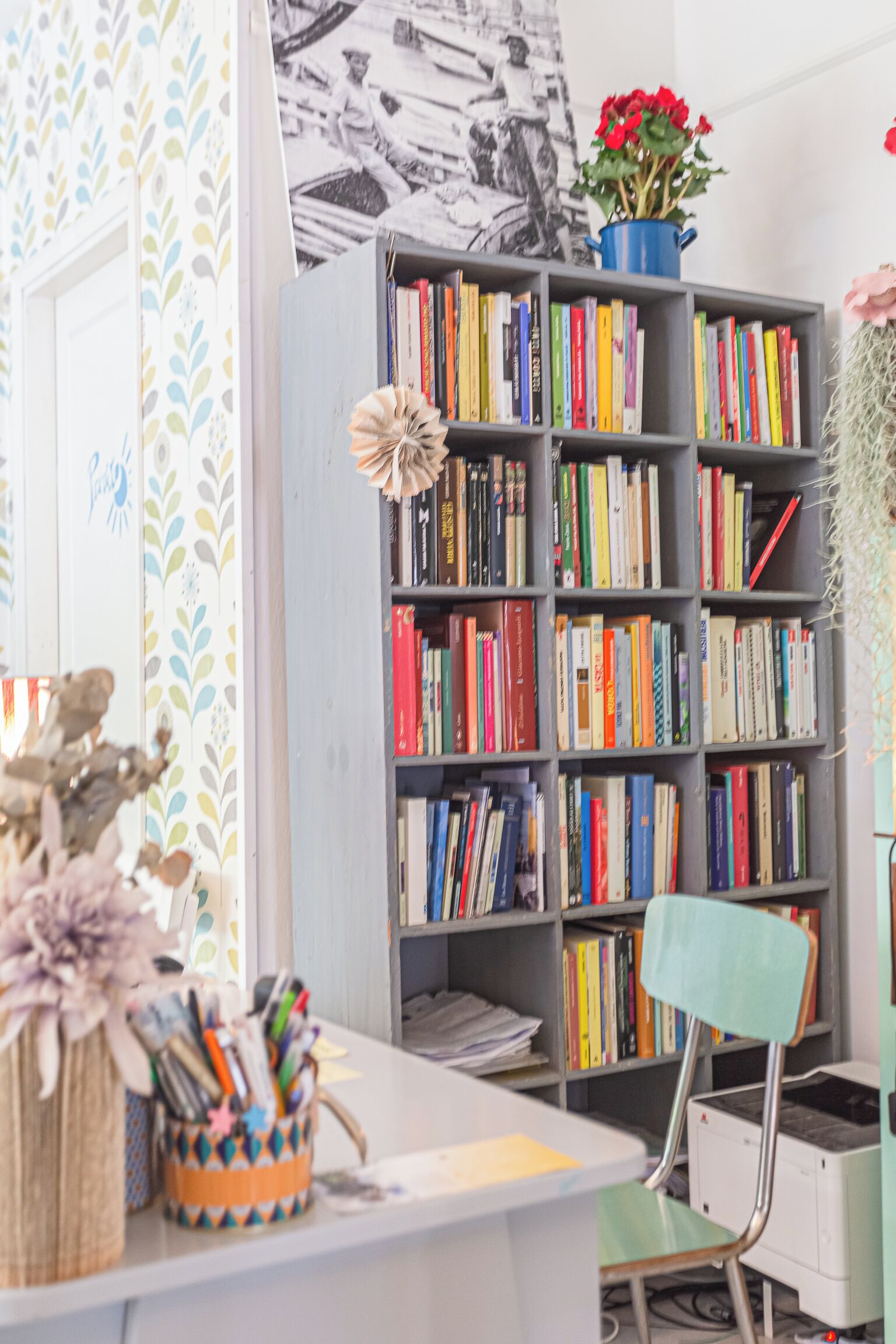 Una habitación con una estantería llena de libros, un escritorio con una silla y una planta en maceta.