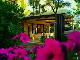 Un hôtel moderne doté d’un espace extérieur aménagé et abrité, entouré d’une végétation luxuriante et de fleurs aux couleurs vives.
