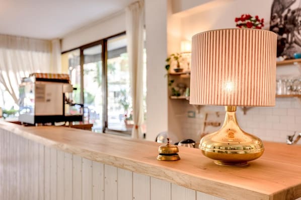 Una zona de bar con mostrador de madera, una lámpara de bronce y una campana.