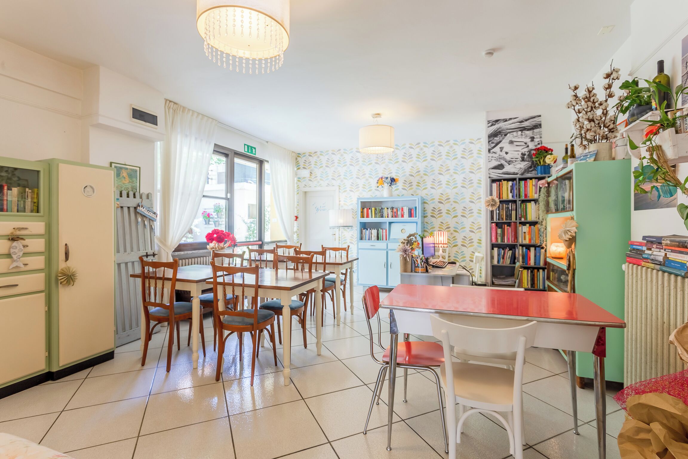 A cozy dining area with a wooden table and chairs, a bookshelf filled with books, and a decorative plant.