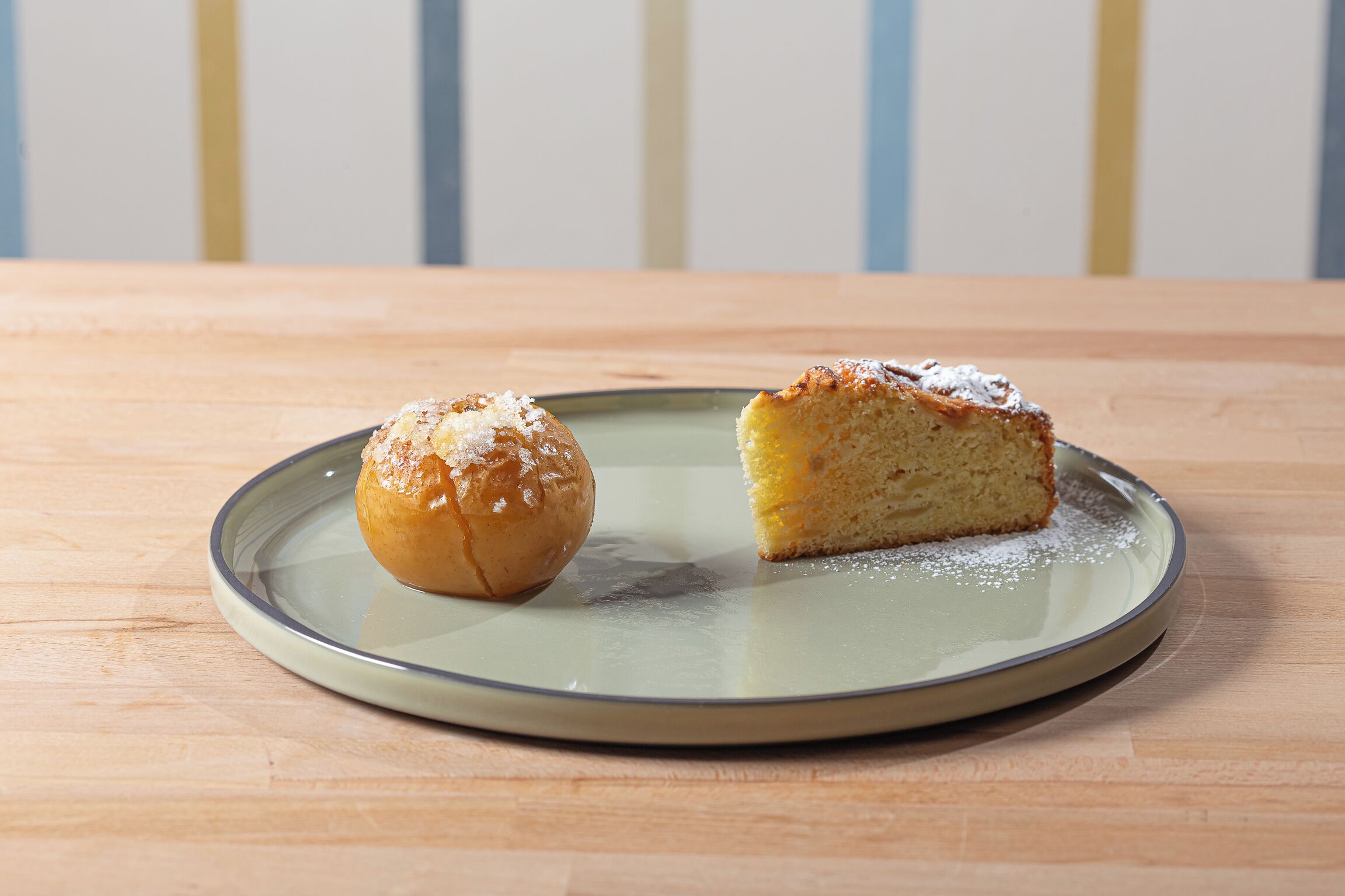 A plate with a pastry and a slice of cake on a wooden table.