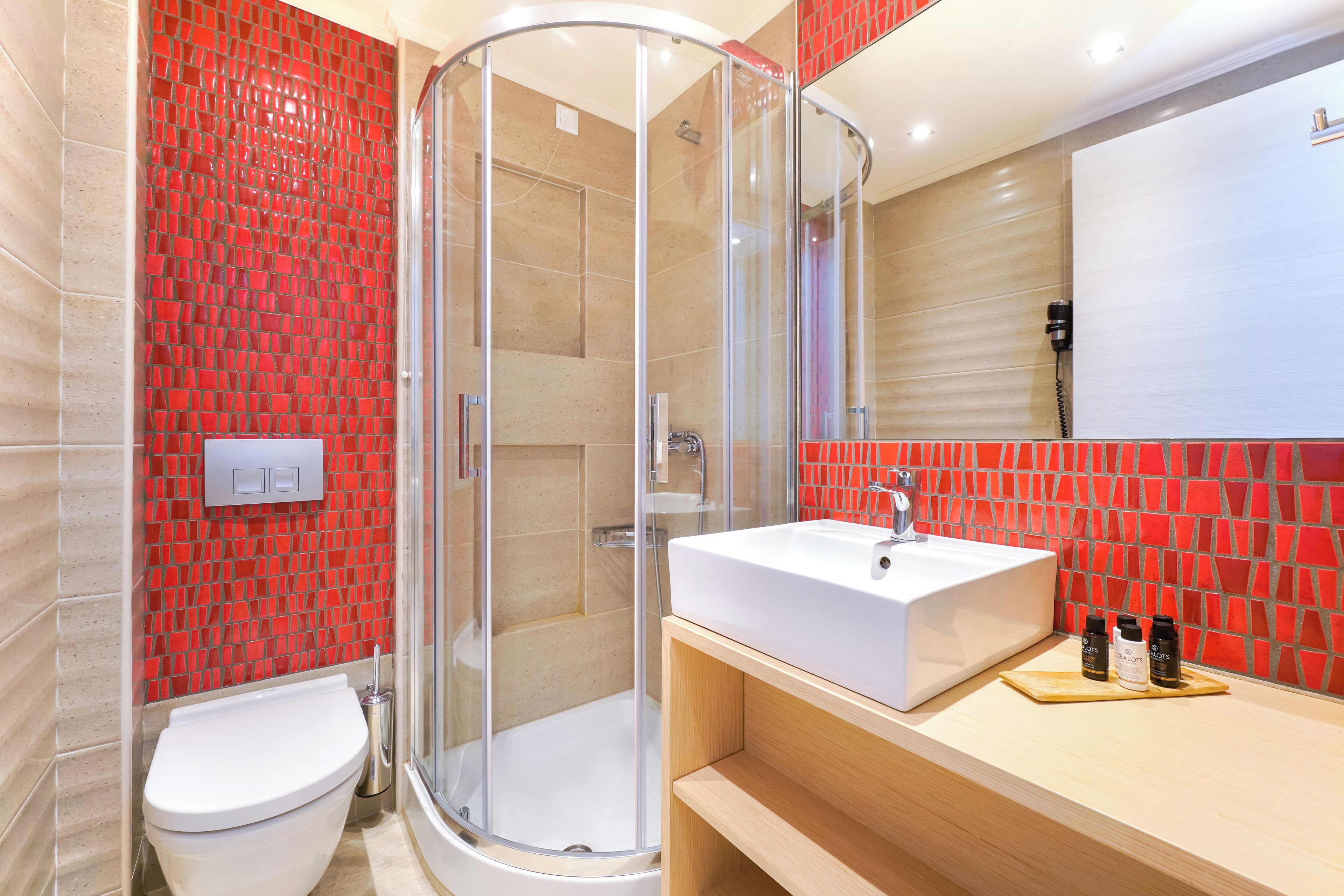 A modern bathroom with a glass-enclosed shower, a white sink, and a red-tiled wall.