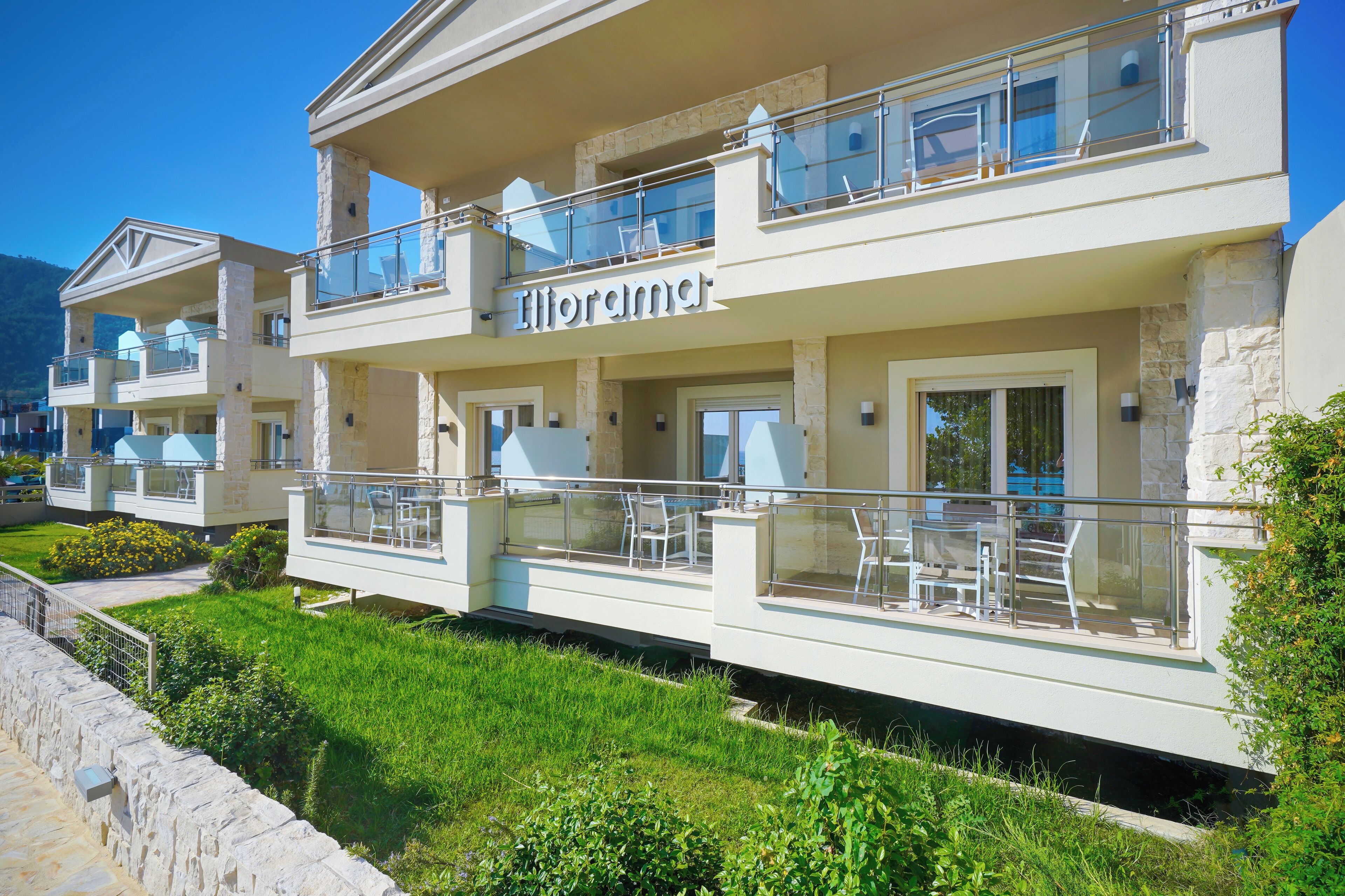 A modern hotel with a two-story structure, outdoor seating areas, and a clear view of the surrounding landscape.