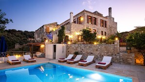 A stone building with a swimming pool and lounge chairs. - Villa Candice (Rethymno)
