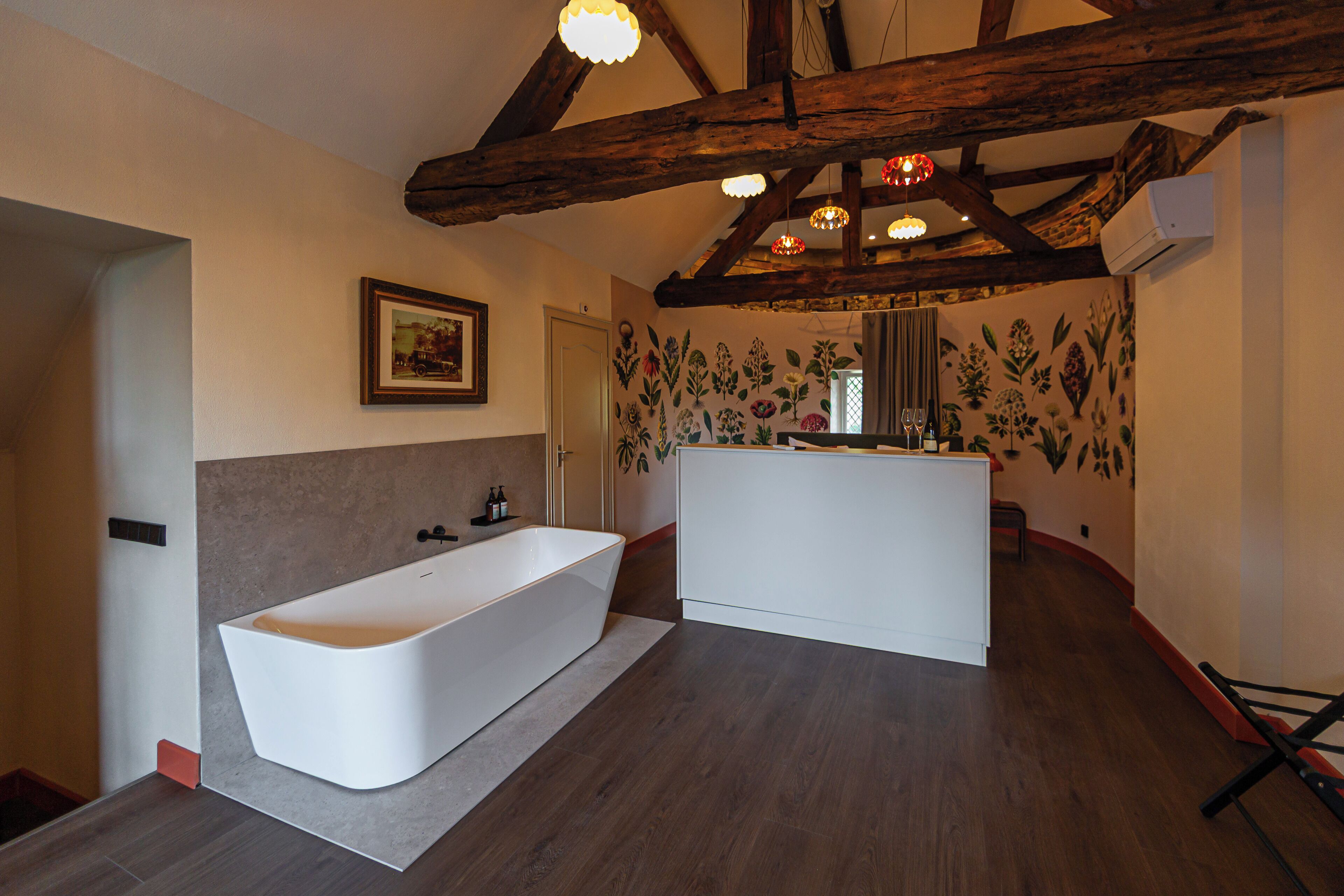 A modern bathroom with a freestanding bathtub, a vanity with a mirror, and a floral wall mural.