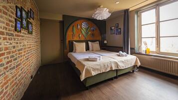Ein Hotelzimmer mit Backsteinwand, großem Fenster und einem Bett mit Blumenbordell.