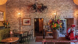 A rustic interior with brick walls, a wooden bar area, and a vintage bicycle mounted on the wall. - Buitenplaats Kasteel Elsloo (Elsloo)