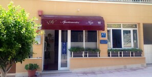 A building with a maroon awning labeled "Apartamentos Niza." - Apartamentos Niza (Calvia)