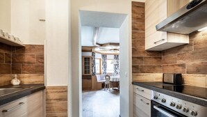 A modern kitchen with wooden accents, a built-in oven, and a dining area with a table and chairs. - Das Filzmoos (Filzmoos)