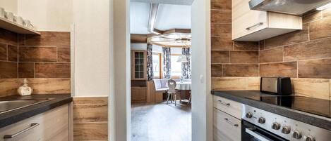 Una cocina moderna con detalles de madera, un horno empotrado y un comedor con mesa y sillas.
