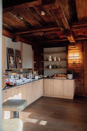 Une cuisine dotée de meubles en bois, d’un bar pour prendre le petit-déjeuner et d’un buffet proposant divers aliments et accompagnements.