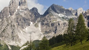 A mountainous landscape with rugged peaks, patches of snow, and green trees. - Das Filzmoos (Filzmoos)