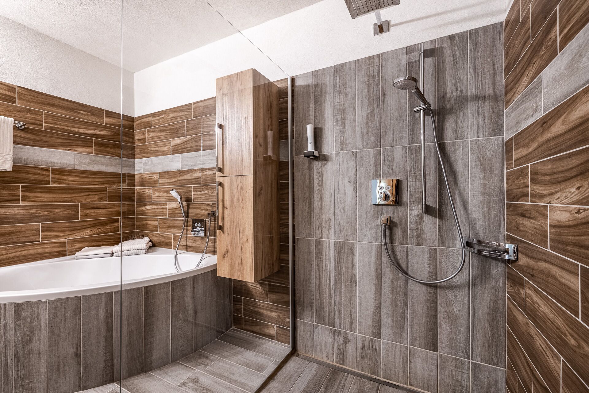 Une salle de bain moderne avec une baignoire sur pieds, une douche à l’italienne dotée d’un pommeau de douche à pluie et des carreaux de mur en bois.